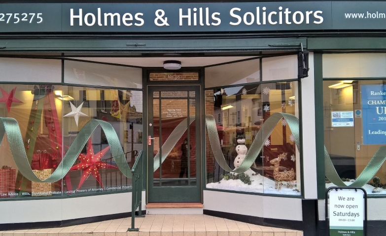 Holmes & Hills Solicitors has chosen not to cut the fir for Christmas and made one from a scale, also they added all over the window display a big tinsel.
