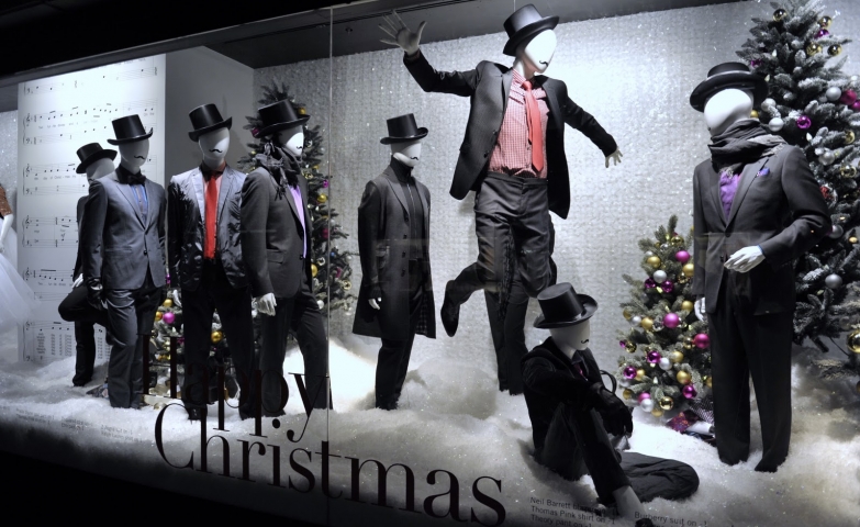Holt Renfrew is wishing happy Christmas through the design of the window display, with mannequins dressed in black costumes, being in contrast with the white background.