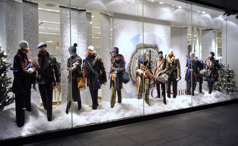 Another Holt Renfrew Christmas window display, with mannequins dressed in different thick clothes, looking like they are on the move and having a conversation.