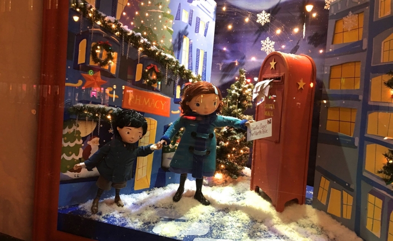 A Christmas window display with a scene in which two kids are sending a letter to Santa.