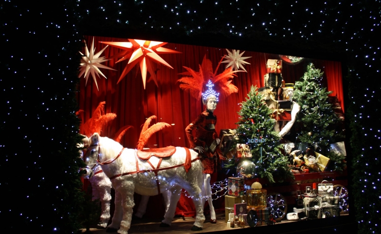 The main theme of this Christmas window display is two little horses with a charged carriage with adorned firs and presents.