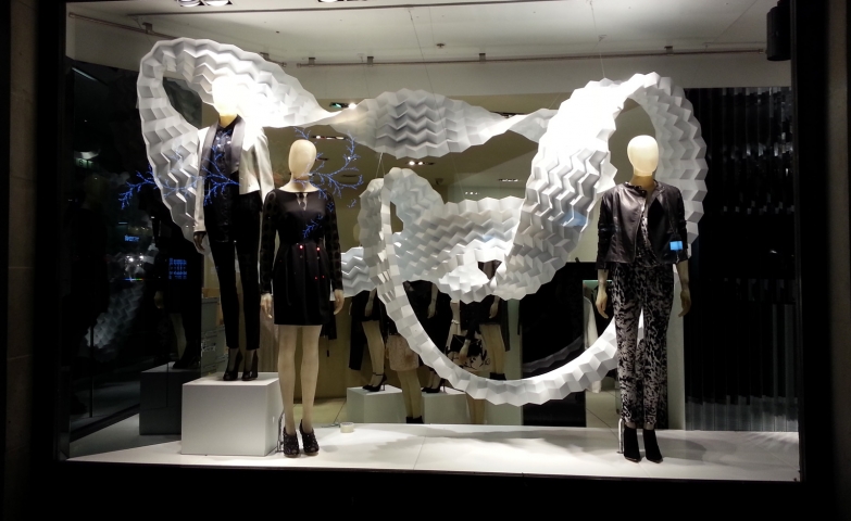 A minimalist Christmas window display, decorated with a long white veil, arranged between the mannequins.