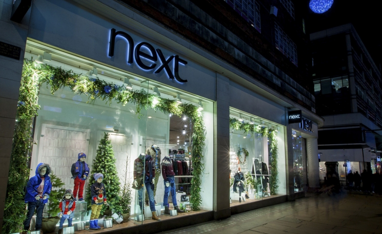 At Next, the Christmas window display is simply decorated with an adorned fir with lights and a decorated window with fir branches.