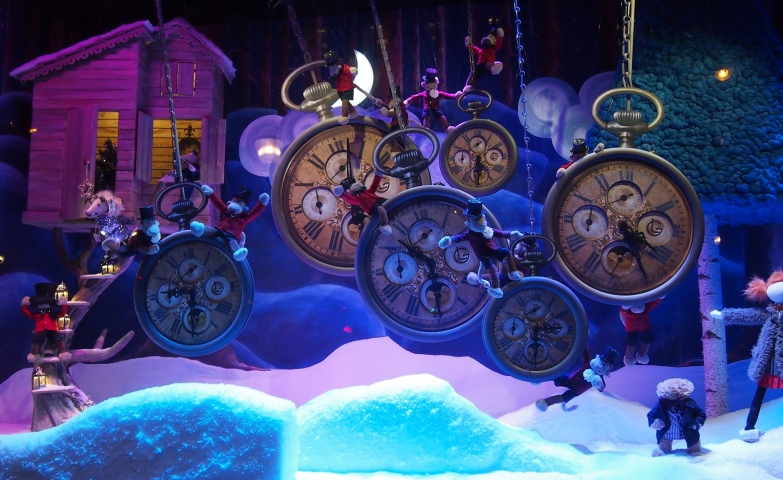 A very rich and sumptuous Christmas window display, with hanging clocks indicating different times, foam snow and puppets.